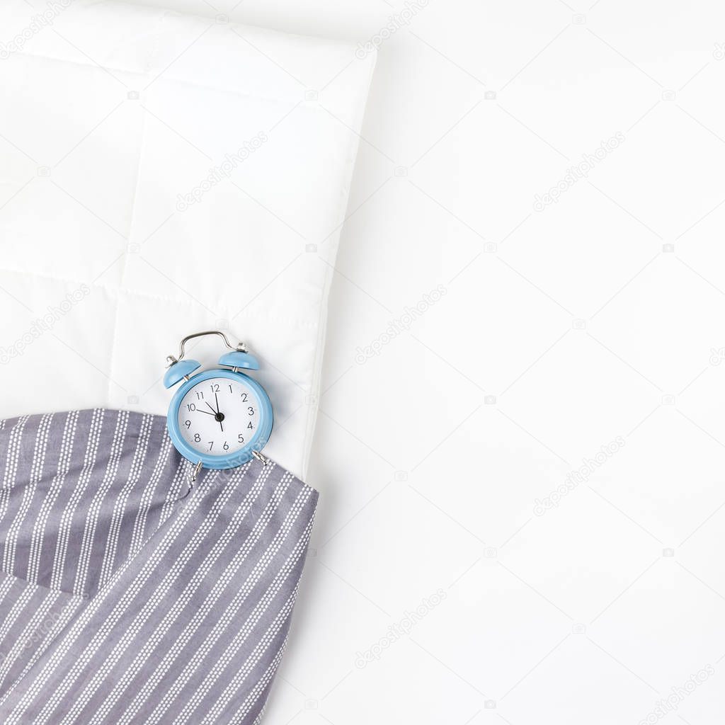 Bed with blue alarm clock on white background