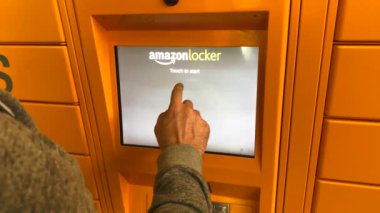 Alışveriş merkezinde Amazon Dolabı 'nı kullanan bir adam, üzerinde Amazon markası logosu olan posta siparişleri için sarı nokta. Lyon, Fransa - 23 Şubat 2020 