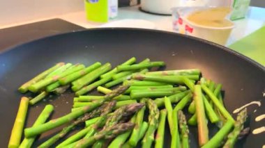 Tavada yeşil kuşkonmaz filizleri pişirmek. 4k yemek hazırlama videosu
