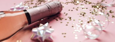 Noel ya da yeni yıl kompozisyonu. İçinde gül şampanyası şişeleri ve pastel pembe arka planda parlak parlak yıldız konfetileri var. Parti Yaratıcı Konsepti