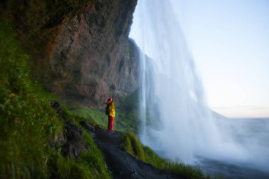 Seljalandsfoss Şelalesi yakınlarındaki kadın turist gün batımında, İzlanda