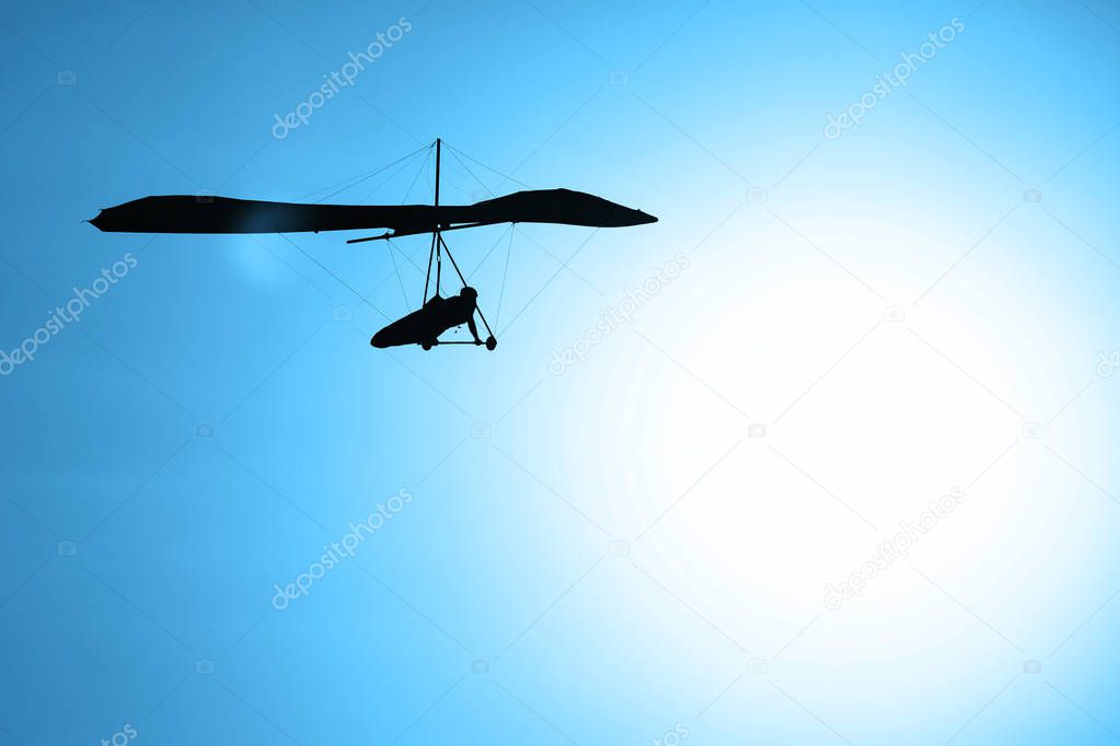 Hang-glider silhouette in sky in sunset time