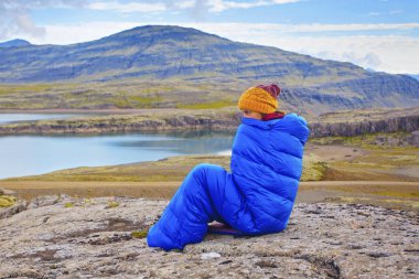 Genç kadın taş Kuzey kütle, İzlanda ile sıcak mavi uyku tulumu