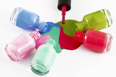 Beyaz arka planda dökülmüş ojeli şişeler.