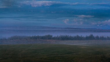 İzlanda'da sisli gün batımı, tarlalar ve tepeler