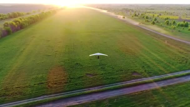 日落时分 滑翔机在绿色和黄色的春田上空盘旋 空中俯瞰 用无人驾驶飞机拍摄 — 图库视频影像