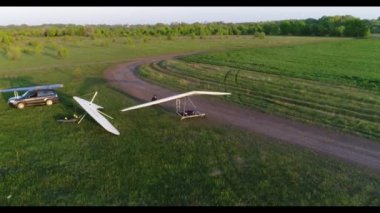 Askılı planör uçuşu günbatımında yeşil ve sarı taze bahar tarlaları üzerinde. Havadan görünüşlü. İnsansız hava aracı ile çekildi.