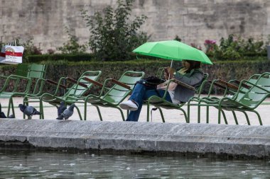 PARIS, FRANCE - 30 Eylül 2016: Tuileries bahçesinde kitap okuyan genç kadın. Tipik Parisli parkta dinleniyor. 