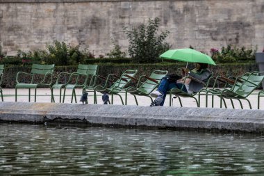 PARIS, FRANCE - 30 Eylül 2016: Tuileries bahçesinde kitap okuyan genç kadın. Tipik Parisli parkta dinleniyor. 