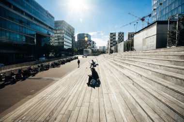Paris, Fransa - 5 Ekim 2016: Paris 'teki Fransız Ulusal Kütüphanesi kuleleri ve güneşli bir günde plazaya çıkan merdivenler, ahşap merdivenlerde kitap okuyan insanlar