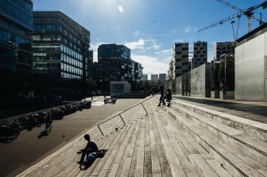 Paris, Fransa - 5 Ekim 2016: Paris 'teki Fransız Ulusal Kütüphanesi kuleleri ve güneşli bir günde plazaya çıkan merdivenler, ahşap merdivenlerde kitap okuyan insanlar
