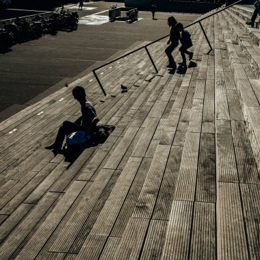 Paris, Fransa - 5 Ekim 2016: Paris 'teki Fransız Ulusal Kütüphanesi kuleleri ve güneşli bir günde plazaya çıkan merdivenler, ahşap merdivenlerde kitap okuyan insanlar