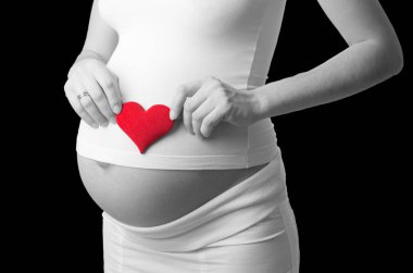 BW hamile kadın kırmızı oyuncak kalp midesi için siyah arka plan üzerine koymak