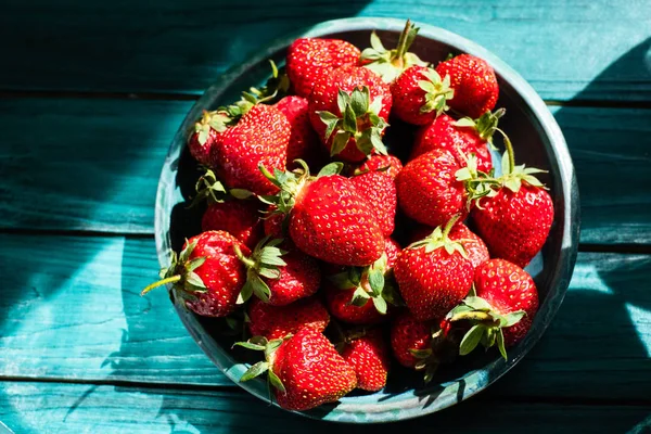 Yeşil plaka üzerinde yeşil ahşap masa güzel fişek ve gölge ile taze çilek