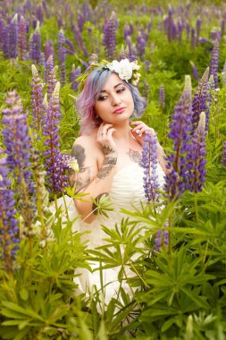 çok renkli saç ve lupines alanında çiçeklerin çelenk ile şehvetli çekici dövme gelin portresi