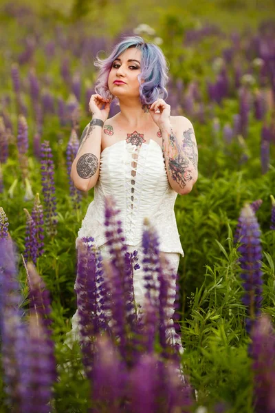 性感诱人的纹身新娘在 Lupines 领域的多色头发和花环 — 图库照片