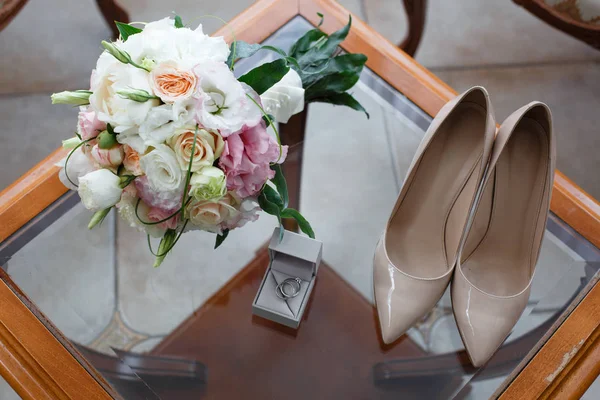 Trauringe Mit Diamant Schuhe Und Ein Brautstrauß Auf Einem Glastisch — Stockfoto