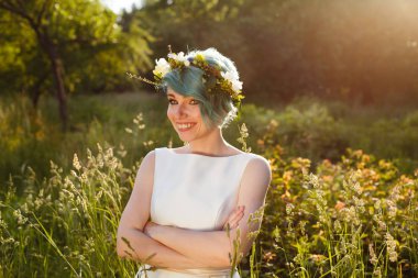 Mavi saçlı ve bir çelenk düğün günü güneşli bir gün ormanda, taze çiçek dolu güzel bir gelin portresi