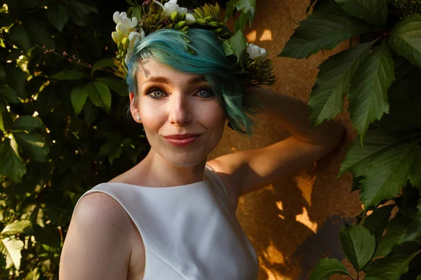 Portrait of a beautiful bride with blue hair and a wreath of real flowers. Wedding day. .A beautiful bride portrait in the forest.