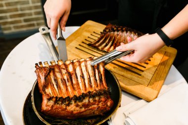 Garson forseps ile gelen bir tavada kızarmış kaburga dışarı alır