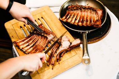 Eller aşçıların kızarmış kaburga bir ahşap tahta üzerinde bir bıçak ile kesmek
