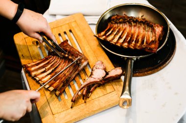 Eller aşçıların kızarmış kaburga bir ahşap tahta üzerinde bir bıçak ile kesmek