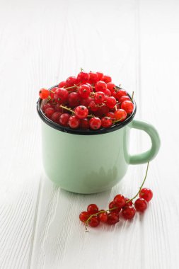 Bir kupa mutfakta bir beyaz tahta masada kırmızı kuş üzümü