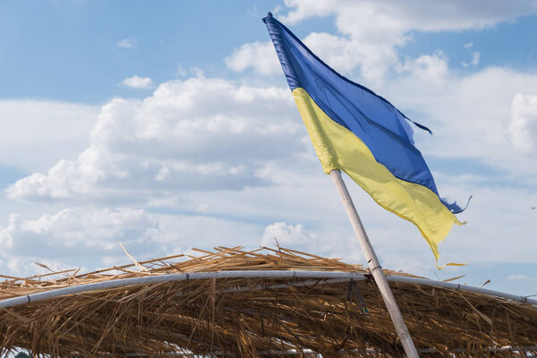 Ukrainian flag on the mast on cloudy background