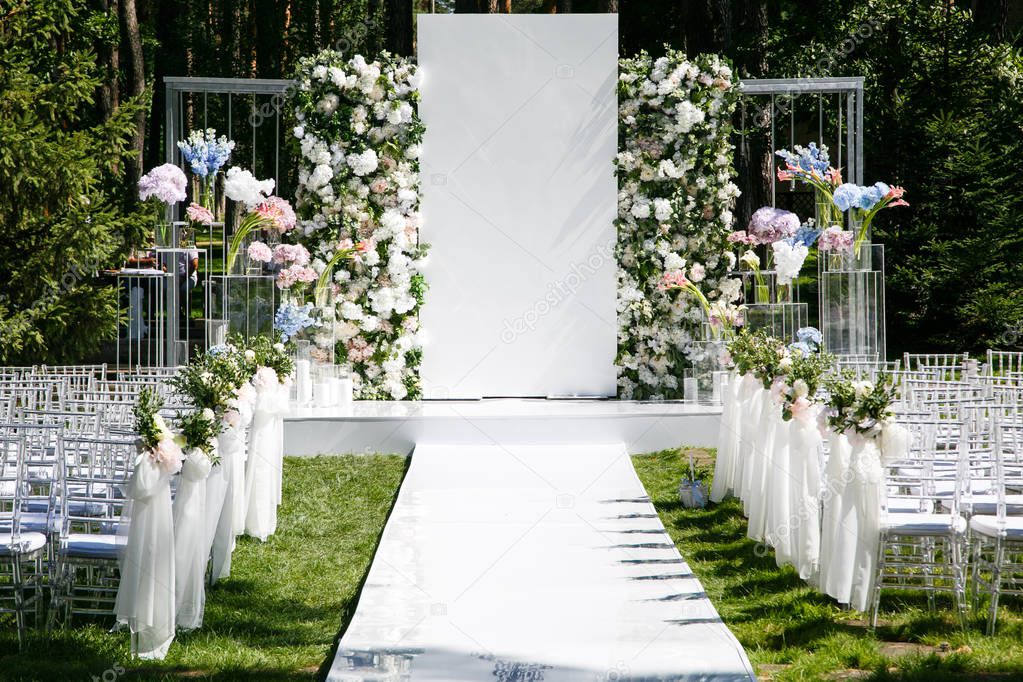 A white walkway leads to a wedding arch decorated with fresh flowers.