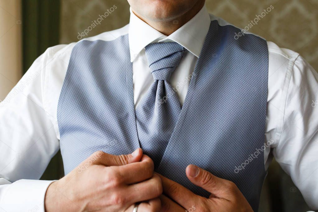 A man puts on an expensive blue suit in the morning.