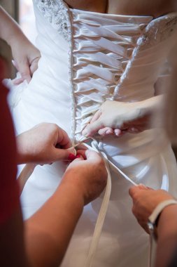 Gelinin gelinliğinin düğmelerini ilikleyen nedime.
