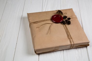 Vintage Noel hediyesi Kraft kağıt sarılı, dize ile bağlı ve mum mühür yapıştırılmış. Beyaz ahşap masanın üzerinde yatan
