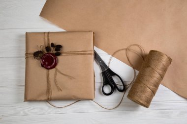 Vintage Noel hediyesi Kraft kağıt sarılı, dize ile bağlı ve mum mühür yapıştırılmış. Beyaz ahşap masanın üzerinde yatan