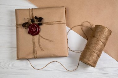 Vintage Noel hediyesi Kraft kağıt sarılı, dize ile bağlı ve mum mühür yapıştırılmış. Beyaz ahşap masanın üzerinde yatan