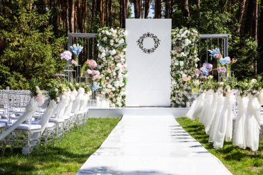 Taze çiçeklerle süslenmiş bir düğün kemer beyaz bir patika yol açar.