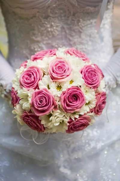Bride wearing gloves holding a bouquet of roses