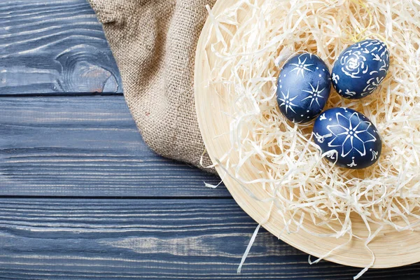 Hand painted dark blue easter eggs in nest and flowers on wooden — Stock Photo, Image