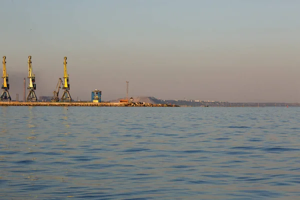 Muitos guindastes grandes silhueta no porto do mar de Azov na luz de ouro do pôr do sol. Mariupol — Fotografia de Stock