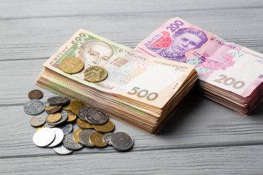Ukrayna 'nın parası. Gri ahşap masanın üzerinde farklı küçük paralarla Ukrayna Hryvnia banknotları yığını