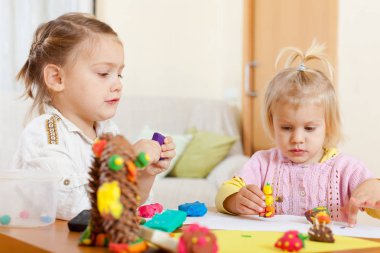 İki genç kız 3 ve 5 yıl eski öğrenme heykeltraşlık hamuru içinde.