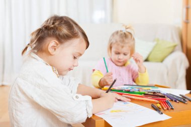 Kızlar evde boya kalemi ile çizim.