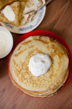 Mutfak masasının üzerinde kırmızı plaka üzerinde krep yığını.