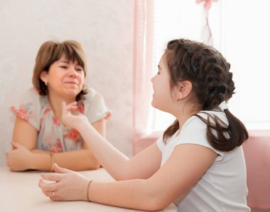 Ergen kız annesiyle evde konuşuyor.