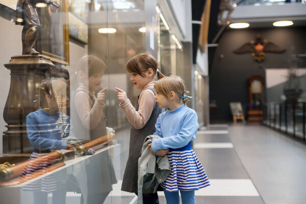  Girls   considering   mock ship in   naval museum.