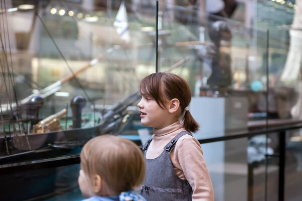  Girls   considering   mock ship in   naval museum.