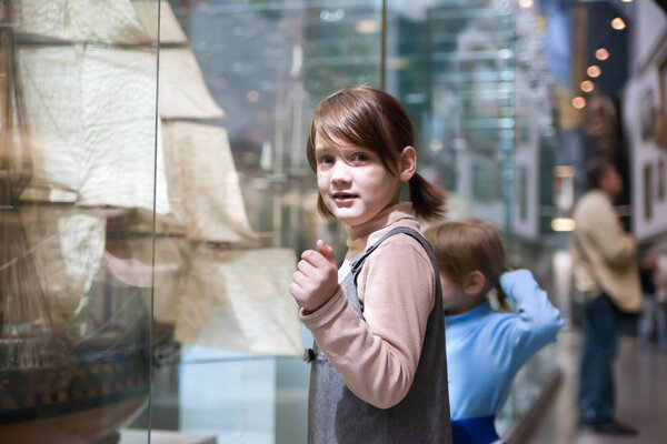  Girl    considering   mock ship in   naval museum.