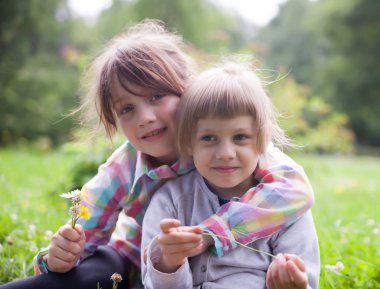 Yaz aylarında sokakta kucaklayan iki kız kardeş.