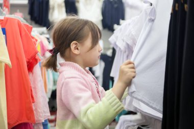   küçük kız okul öncesi giysiler deposunda seçmek