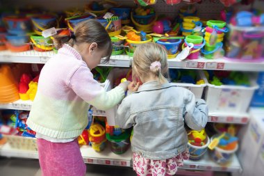 Two girlfriends choosing   gift in   toy store clipart