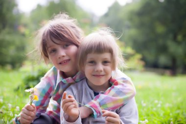 Yaz aylarında sokakta kucaklayan iki kız kardeş.